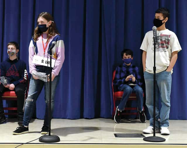 Lilly Graham from Piqua Catholic School, standing left, and Elijah Amick from Piqua Junior High School, standing far right, face off as the final two contestants in Thursday’s Piqua City-Wide Spelling Bee at Piqua Central Intermediate School. Amick finished the night as the Piqua Spelling Bee champion while Graham was runner-up. The annual event is sponsored by the Piqua Kiwanis Club.